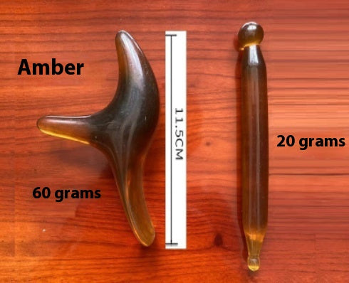 Amber massage tools weighing 60 grams and 20 grams on a wooden surface, with a height of 11.5 cm.